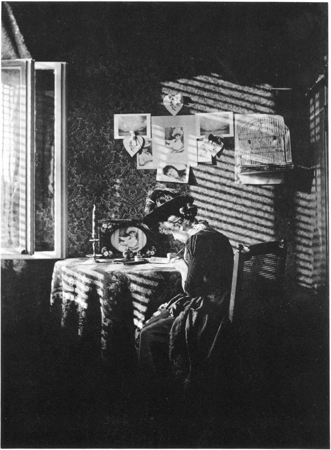 Alfred Stieglitz, Paula (Sun Rays), Berlin, 1889. A young woman writes at a desk by a window, lit by diagonal beams of sunlight.