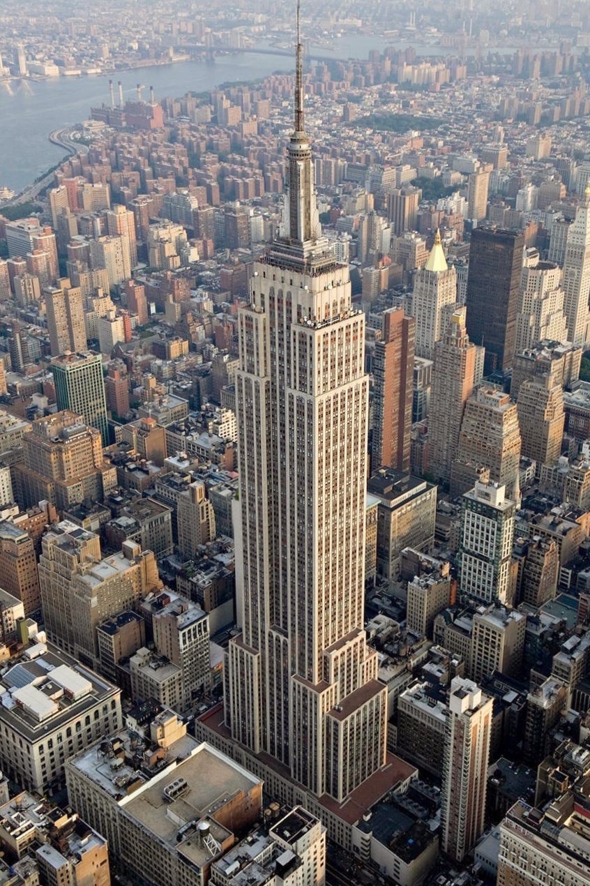 Aerial view of the stepped, tapering tower of the Empire State Building rising above Manhattan.