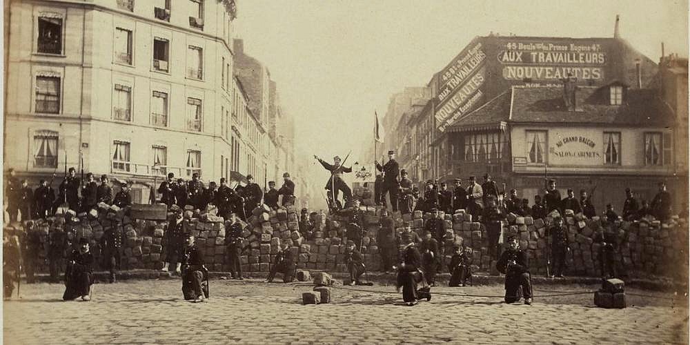 Anonymous, Barricades during the Paris Commune, 1871. A lithograph depicting street barricades in Paris, with figures visible in the foreground against a backdrop of smoke and urban buildings.
