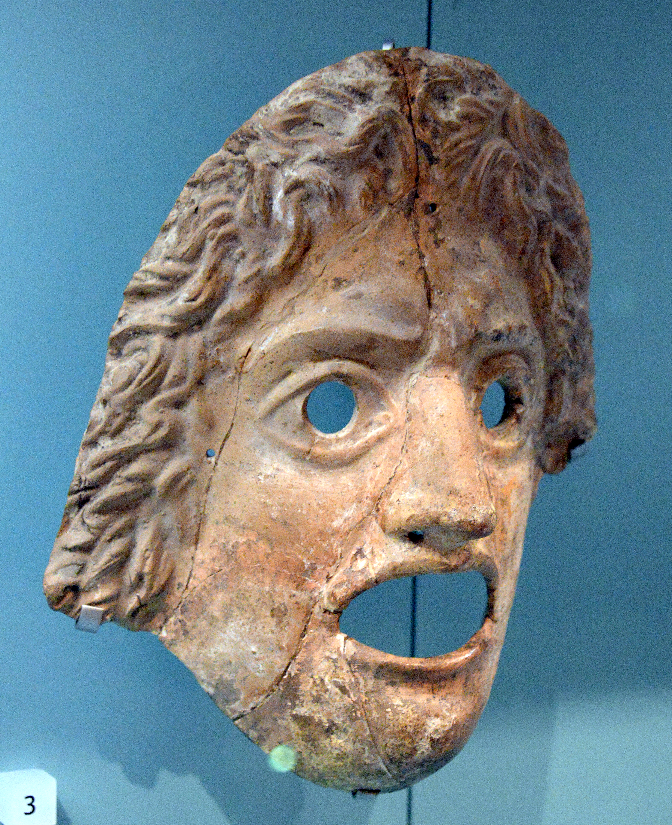 A classical theater mask in profile, its features frozen in an expression of anguish or sorrow. The mask illustrates Sartre's concept of bad faith: the attempt to fix a role as if it were an immovable essence rather than a chosen performance.