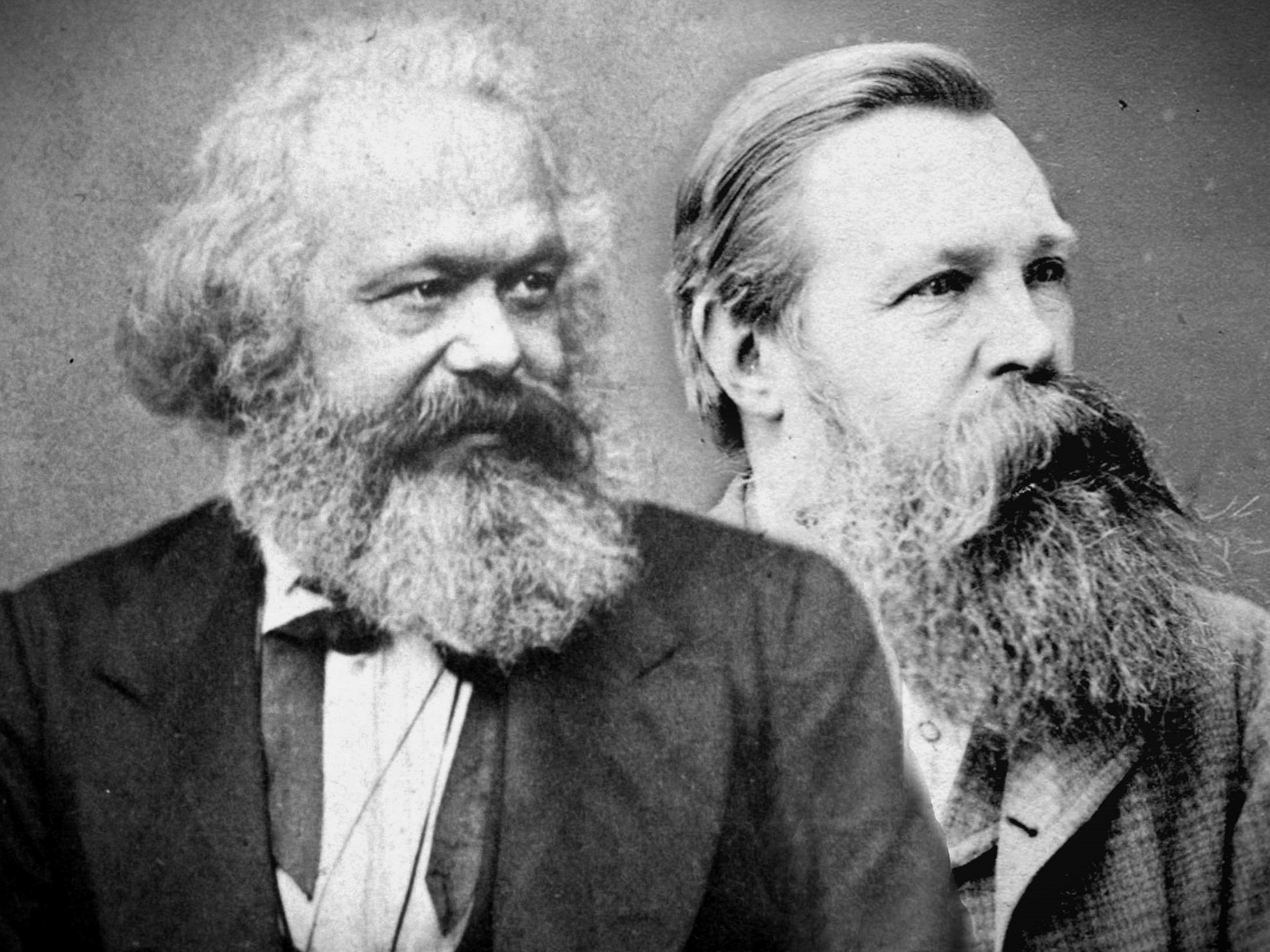 Photograph of Karl Marx and Friedrich Engels, c. 1875. Two young men in nineteenth-century formal dress stand side by side, looking directly at the camera.