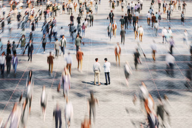 Photograph of a crowd of people in an urban setting, with individuals moving in different directions.