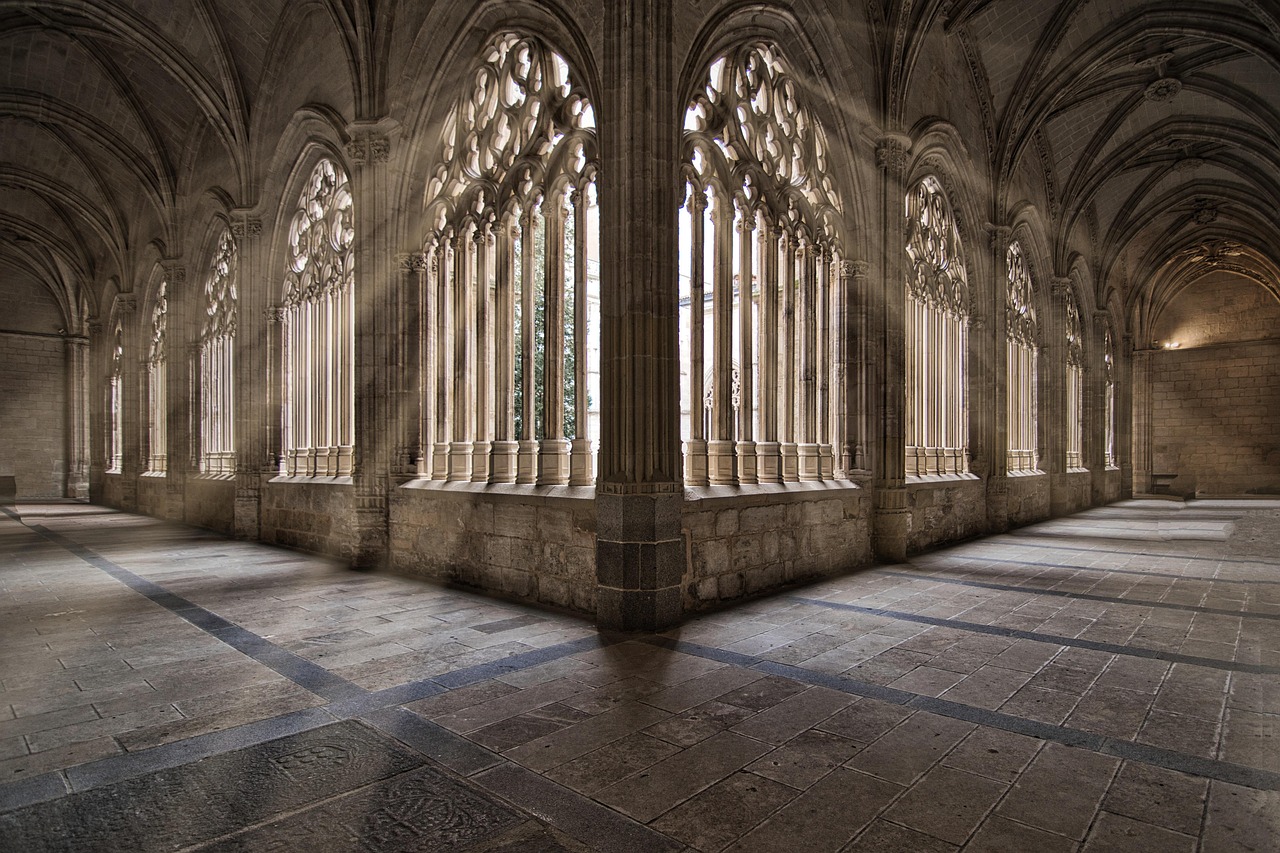 Beautiful interior of a Gothic church with stained glass windows and sunlight streaming in from the arched windows.